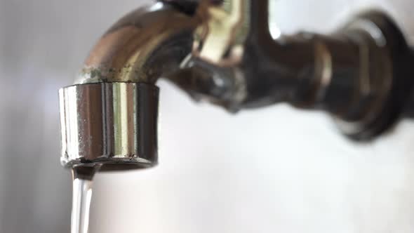 Water Drops Dripping From an Old Defective Faucet Macro