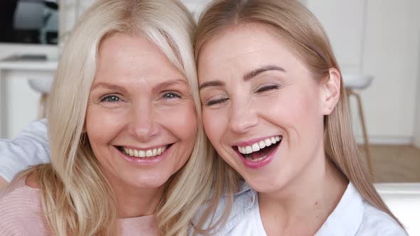 Closeup Portrait of Happy Adult Daughter Hugging Her Elderly Mother Hugging and Looking at Camera