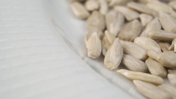 Healthy peeled dried sunflower seeds fall in slow motion into a white plate