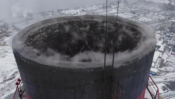 Aerial Survey Over the Tops of Two Smoking Factory Pipes and the Snow-capped City Lying Below alt
