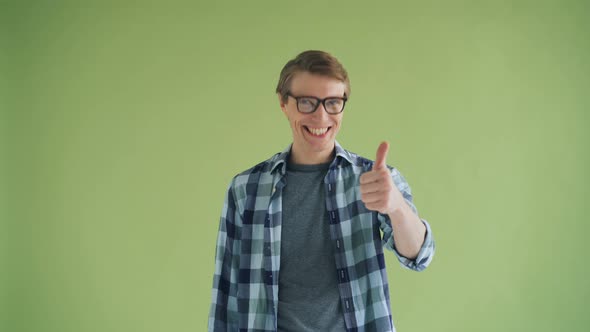 Portrait of Cheerful Male Showing Thumbs-up and Smiling on Green Background