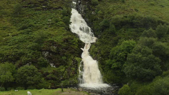 Aerial zoom out shot of beautiful waterfall in remote landscape, Ireland