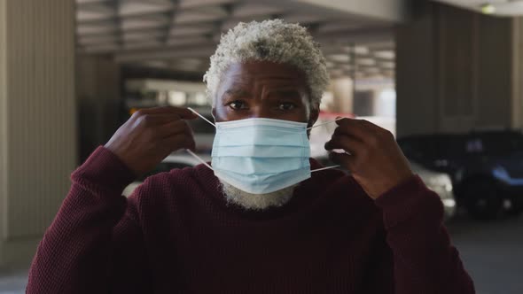 Portrait of african american senior man wearing face mask in the parking lot