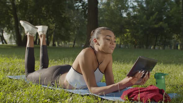 Woman with Tablet Pc Relaxing After Workout in Park