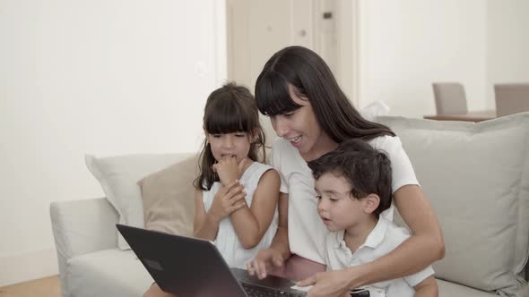Happy Mom and Two Cute Kids Using Laptop Together