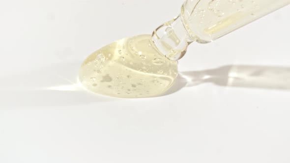 Liquid Fluid Yellow Gel or Serum in Pipette Drips on a White Surface