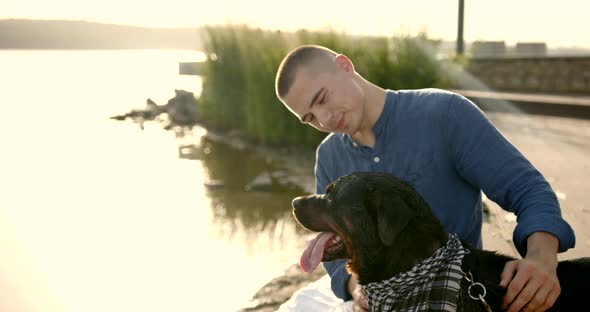 Young Man Spending Time with His Dog Be River Bank