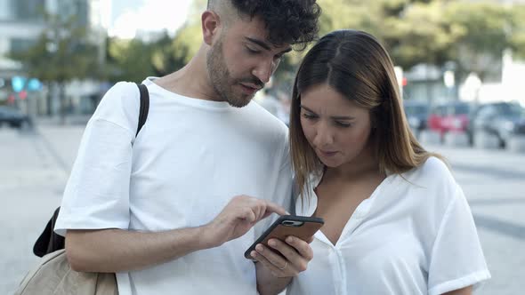 Focused Young Couple Looking at Smartphone 