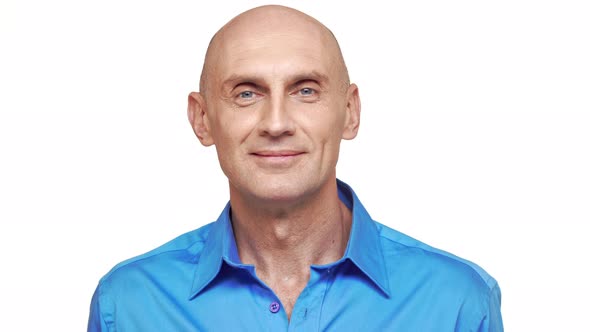 Middleaged Bold Caucasian Male in Blue Shirt Standing on White Background and Smiling