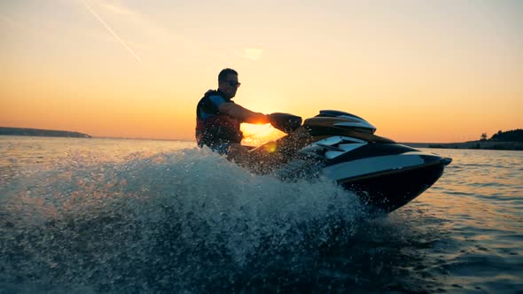 A Man Is Riding a Jet-ski Along the Coastline During Sunset