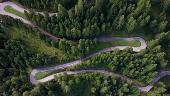 Winding road with red car going up the mountain in the Dolomite area of northern Italy, Aerial drone