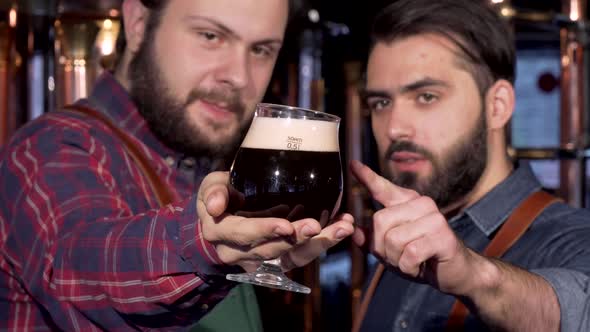 Selective Focus on a Glass of Dark Beer in Hands of a Brewer