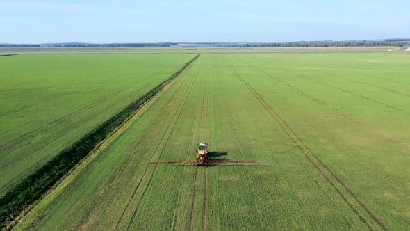 Farm Tractor Spraying Herbicides And Pesticides Fertilizer On Green Rural Field