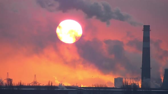 Sunrise over an industrial factory time lapse. The chimney fumes air pollution. Fuming chimneys.