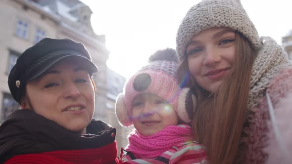 Women Tourists Taking Selfie Photos on Mobile Phone with Adoption Child Girl on Winter City Street