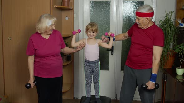 Granddaughter and Mature Grandparents in Sportswear Making Sports Jogging Workout Exercises at Home