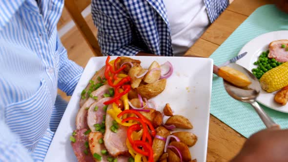 Woman serving meal to man on dining table