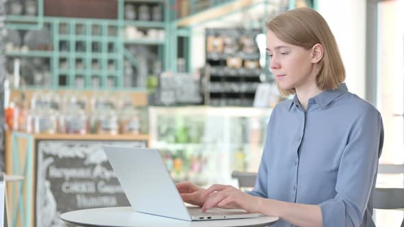 Young Woman Working on Laptop in Cafe