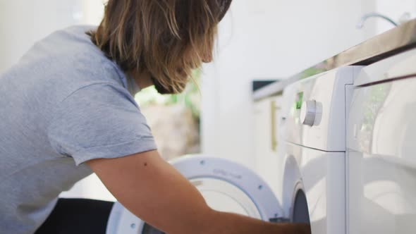 Caucasian man putting apron in the washing machine at home