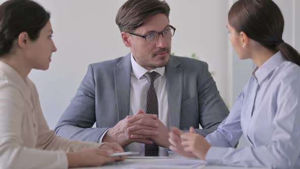 Male and Female Business Person Discussing Documents in Office