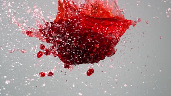Pomegranate juice with seeds exploded and splashed in the air. Slow Motion.