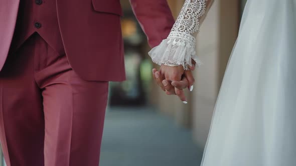 Groom in Tuxedo and Bride in Vintage Gown Hold Hands Walking