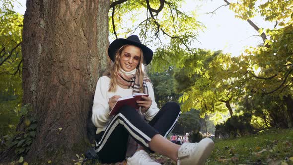 Young Woman Making Some Notes in her Diary While Sitting