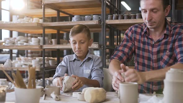 Attractive Caucasian Man and Liitle Cute Boy Kneading Clay for Pots