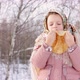 Cute girl in a traditional Russian headscarf with bagels eats pancake on winter background. - VideoHive Item for Sale