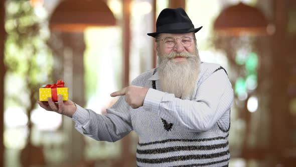 Old Longbearded Man Pointing at Gift Box with Finger