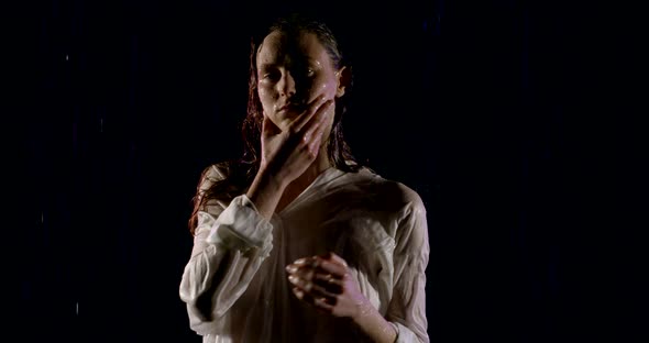 Sexual Slim Woman Dressed in White Male Shirt Is Standing Under Water Flows in Darkness, Posing for