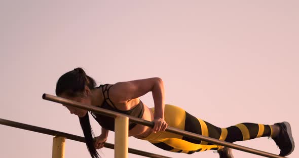 A Beautiful Woman at Dawn Performs pushUPS on Parallel Bars in Slow Motion