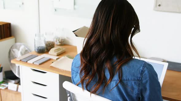 Female executive sitting at desk and using digital tablet