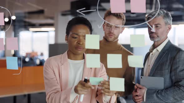 Close Up of Female Office Worker Using Glass Board and Proposing Her Problem Solving to Workmates