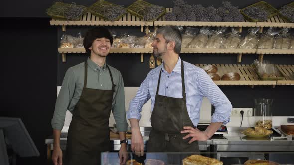 Close Up Portrait of Happy Father and Son Family Business Owners High Five in Their Bakery Store