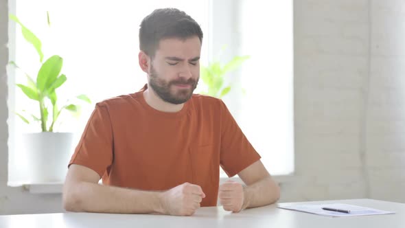 Upset Young Man Worried While Sitting in Office