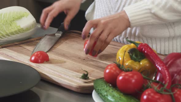 Cropped Shot of a Woman Slicing Tomato on a Wooden Cutting Board