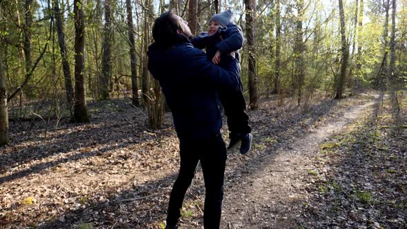 Father in a Blue Hooded Jacket Throws His Young Son