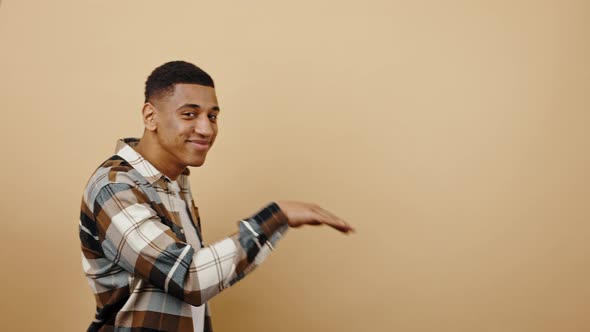 Young Happy African American Man Moving Aside Dancing Egyptian Style and Smiling to Camera Beige