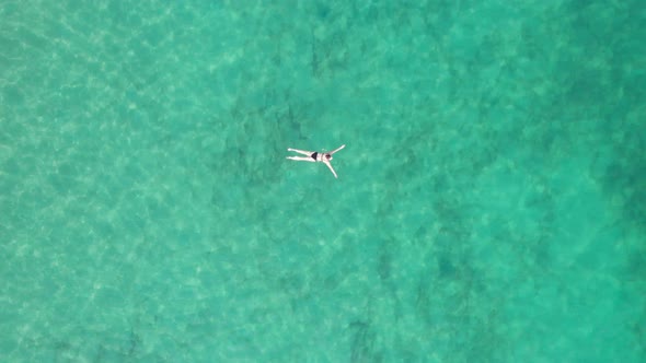 Top Down Aerial View of Woman Swims on Crystal Clear Water in a Transparent Sea