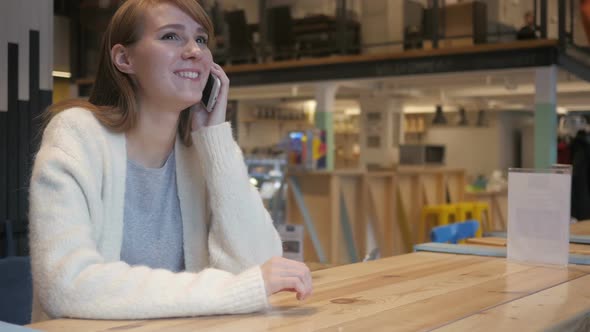 Young Woman Talking on Phone While Sitting in Cafe