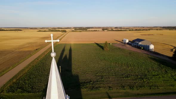 Aerial footage of roman catholic church in north American prairie during sunset. White building with