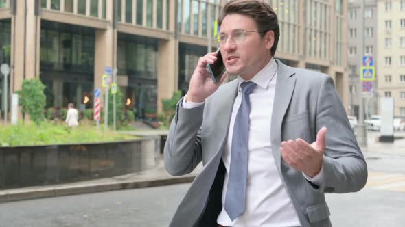 Businessman getting Angry on Call while Walking on Street