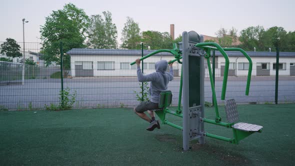 Man doing lat pulldowns. Evening workout in an outdoor gym. Health and fitness