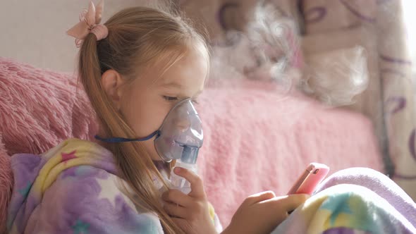 Little Girl Holds Inhaler Mask at Home. Sick Kid Breathes Through a Nebulizer. Baby Using Equipment