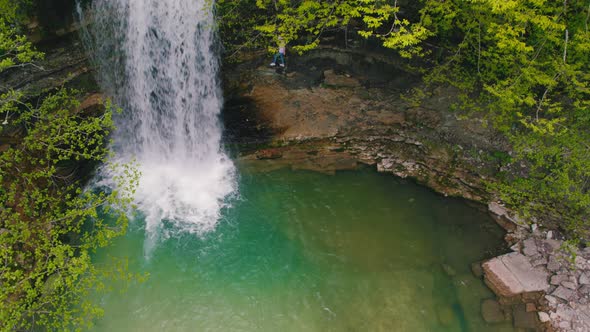 Topdown View of a Waterfall and s Small Green Lake