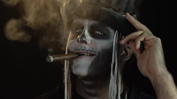 Sinister Man with Horrible Halloween Holiday Skeleton Makeup Raising His Head and Smoking Cigar