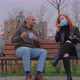 Man and Woman Sitting on Park Bench Take Off Their Protective Masks and Begin to Communicate - VideoHive Item for Sale