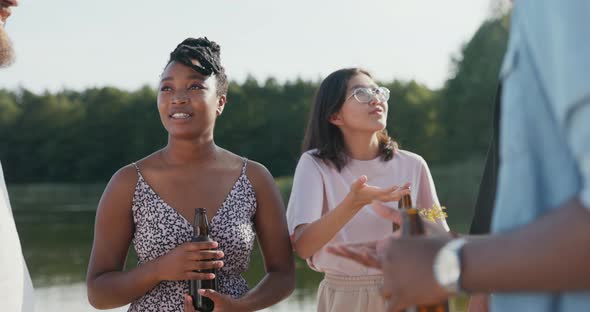 A Group of Friends are Relaxing Together Spending a Vacation a Summer Afternoon By the Lake Drinking