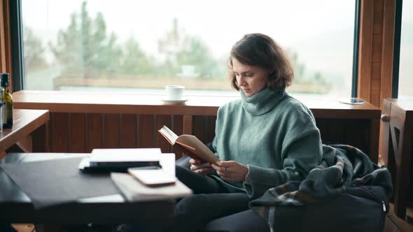 A Young Woman Sitting in Her Living Room and Reading a Book